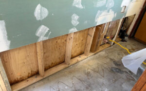 With saturated drywall removed, the wooden studs and subfloor are fully exposed to allow for rapid, professional structural drying and mitigation.